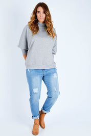 Model Laura wearing size L of The Batwing Jumper in colour Greyfleck (Grey), from the front, showing the whole outfit