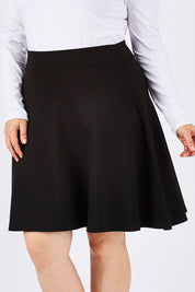 Model Ljubenka wearing size 18 of The Ponte Flip Skirt in colour Black (Black), from the front, cropped image