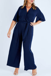 Model Fiona wearing size 16 of The Bell Sleeve Jumpsuit in colour Navy (Blue), from the front, cropped image
