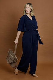 Model Jess wearing size 14 of The Bell Sleeve Jumpsuit in colour Navy (Blue), from the front, showing the whole outfit