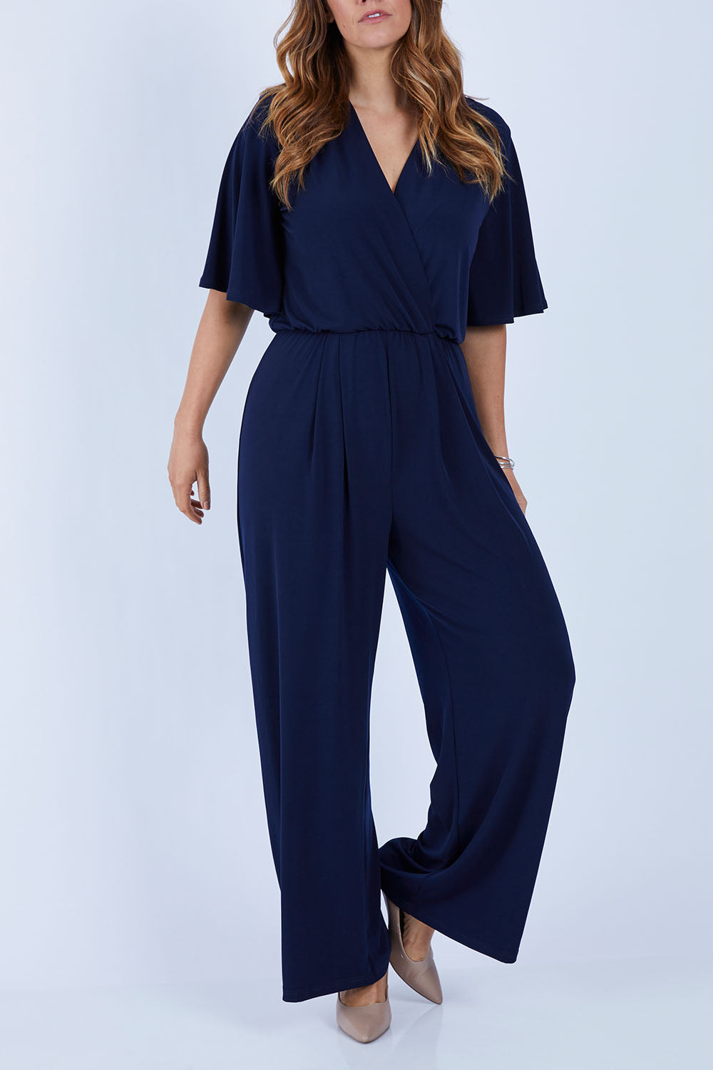 Model Laura wearing size 12 of The Bell Sleeve Jumpsuit in colour Navy (Blue), from the front, cropped image