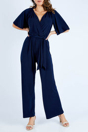 Model Madeline wearing size 10 of The Bell Sleeve Jumpsuit in colour Navy (Blue), from the front, cropped image