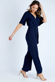 Model Madeline wearing size 10 of The Bell Sleeve Jumpsuit in colour Navy (Blue), from the front, showing the whole outfit
