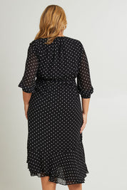Model Fiona wearing size 16 of The Printed Chiffon Puff Sleeve Dress in colour Polkadot (Black), from the back