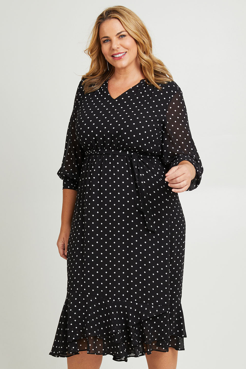 Model Fiona wearing size 16 of The Printed Chiffon Puff Sleeve Dress in colour Polkadot (Black), from the front, cropped image