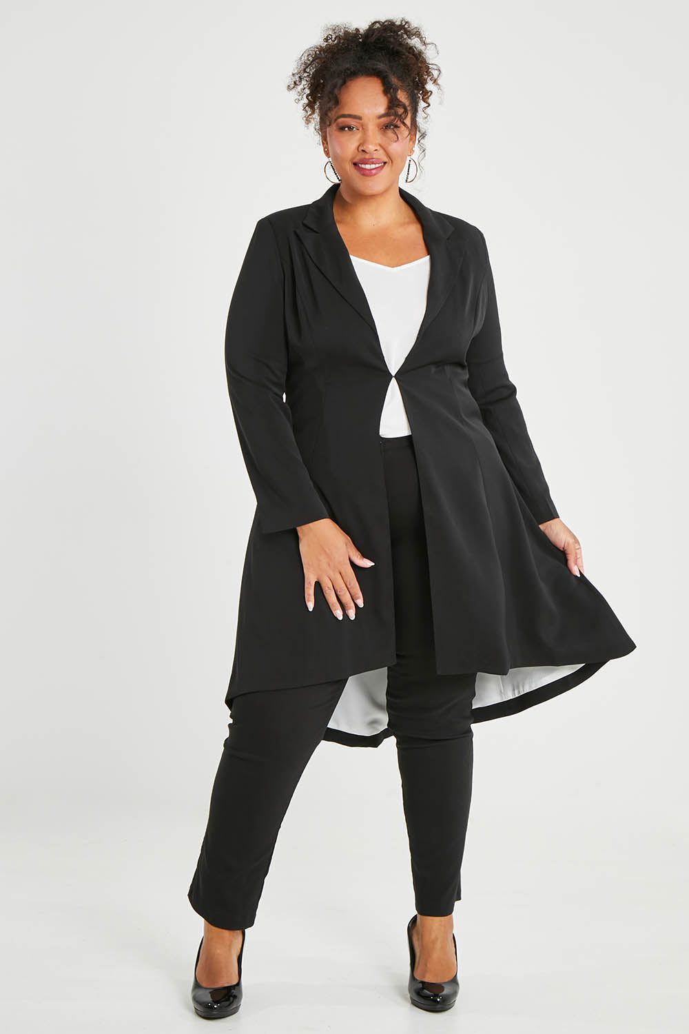 Model Alexis wearing size 16 of The Tailored Longline Jacket in colour Black (Black), from the front, showing the whole outfit