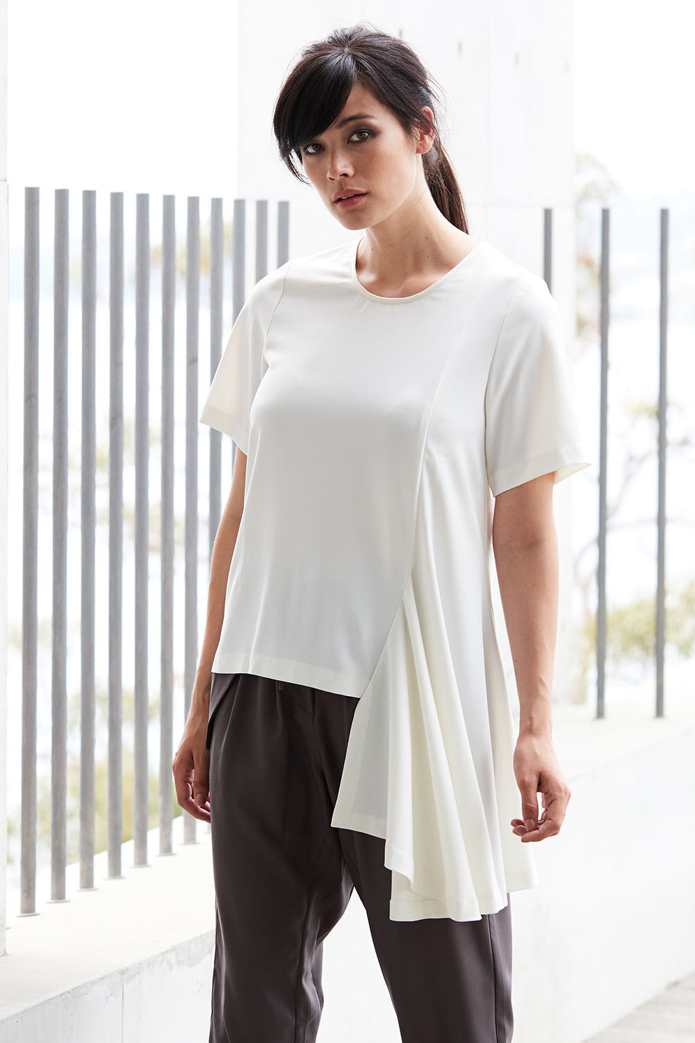 Model Miranda wearing size 10 of The Side Panel Drape Top in colour OffWhite (White), from the front, showing the whole outfit