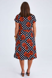 Model Monique wearing size 14 of the Belle Cotton Sateen Print Pleat Dress in colour Rosespot (Black), from the back