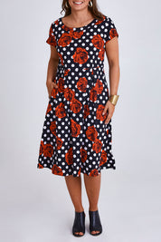 Model Monique wearing size 14 of the Belle Cotton Sateen Print Pleat Dress in colour Rosespot (Black), from the front, cropped image