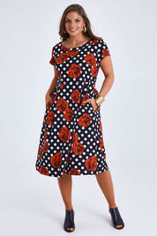 Model Monique wearing size 14 of the Belle Cotton Sateen Print Pleat Dress in colour Rosespot (Black), from the front, showing the whole outfit