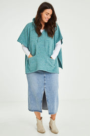Model Laura wearing size M-L of the Keeping The Chill Out Poncho in colour Sea (Blue), from the front, showing the whole outfit