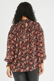 Model Noli wearing size 14 of the Romance In The Air Blouse in colour Blkrust (Black), from the back