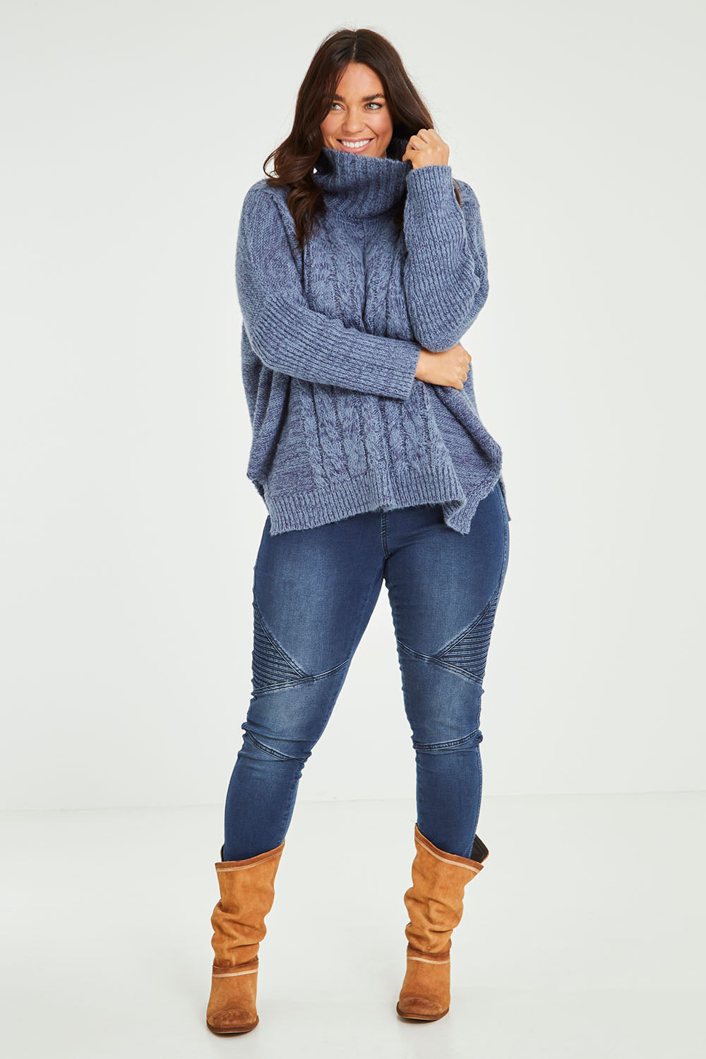 Model Laura wearing size M-L of the Cool Breeze Cable Sweater in colour Denim (Blue), from the front, showing the whole outfit