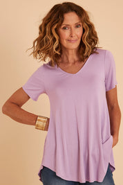 Model Emma wearing size 10 of the Softly Swinging Bamboo Tee in colour Lilac (Purple), from the front, cropped image