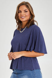 Model Monique wearing size 14 of the Flutter By Tee in colour Marldenim (Blue), from the front, cropped image