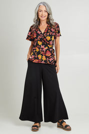 Model Luisa wearing size 10 of the All For You Wrap Top in colour Blkfleur (Black), from the front, showing the whole outfit