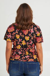 Model Monique wearing size 14 of the All For You Wrap Top in colour Blkfleur (Black), from the back