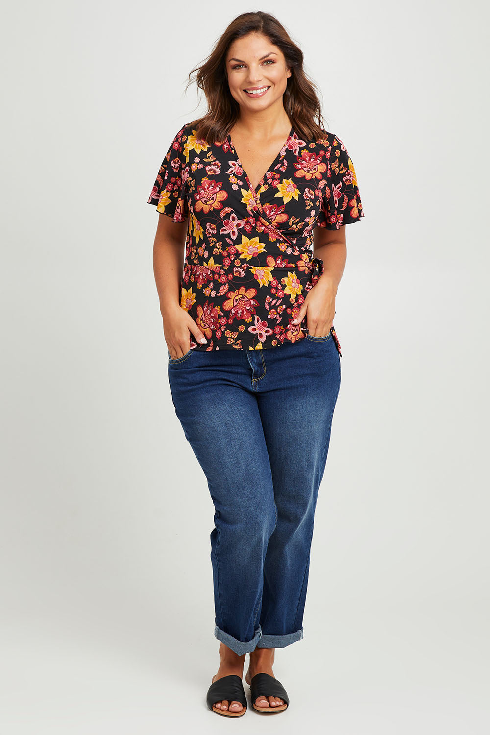 Model Monique wearing size 14 of the All For You Wrap Top in colour Blkfleur (Black), from the front, showing the whole outfit