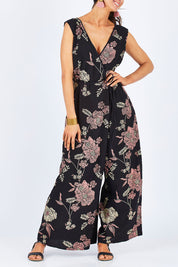 Model Gemma wearing size 10 of the Illusion Faux Wrap Jumpsuit in colour Blackfleur (Black), from the front, cropped image