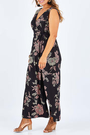 Model Palatina wearing size 14 of the Illusion Faux Wrap Jumpsuit in colour Blackfleur (Black), from the front, cropped image