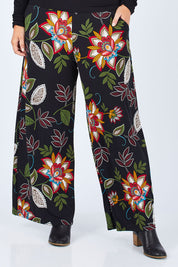 Model Jess wearing size 14 of the Falling Leaves Wide Leg Pant in colour Black (Black), from the front, cropped image