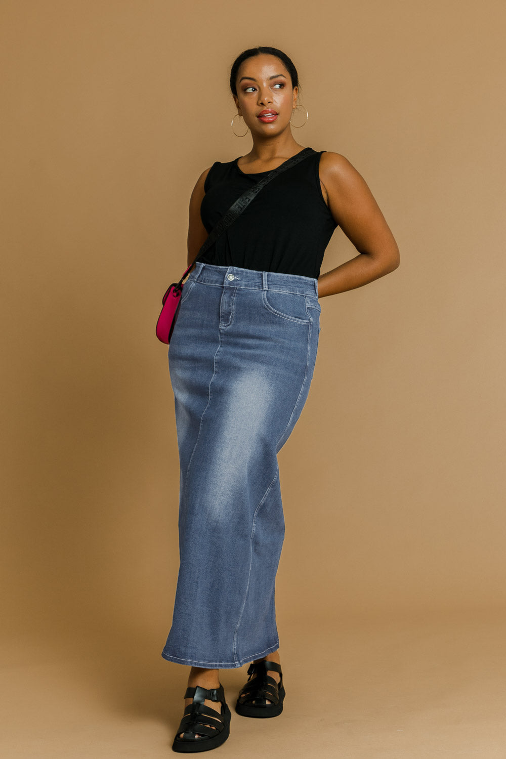 Model Noli wearing size 14 of the Dusty Footprints Skirt in colour Denim (Blue), from the front, showing the whole outfit