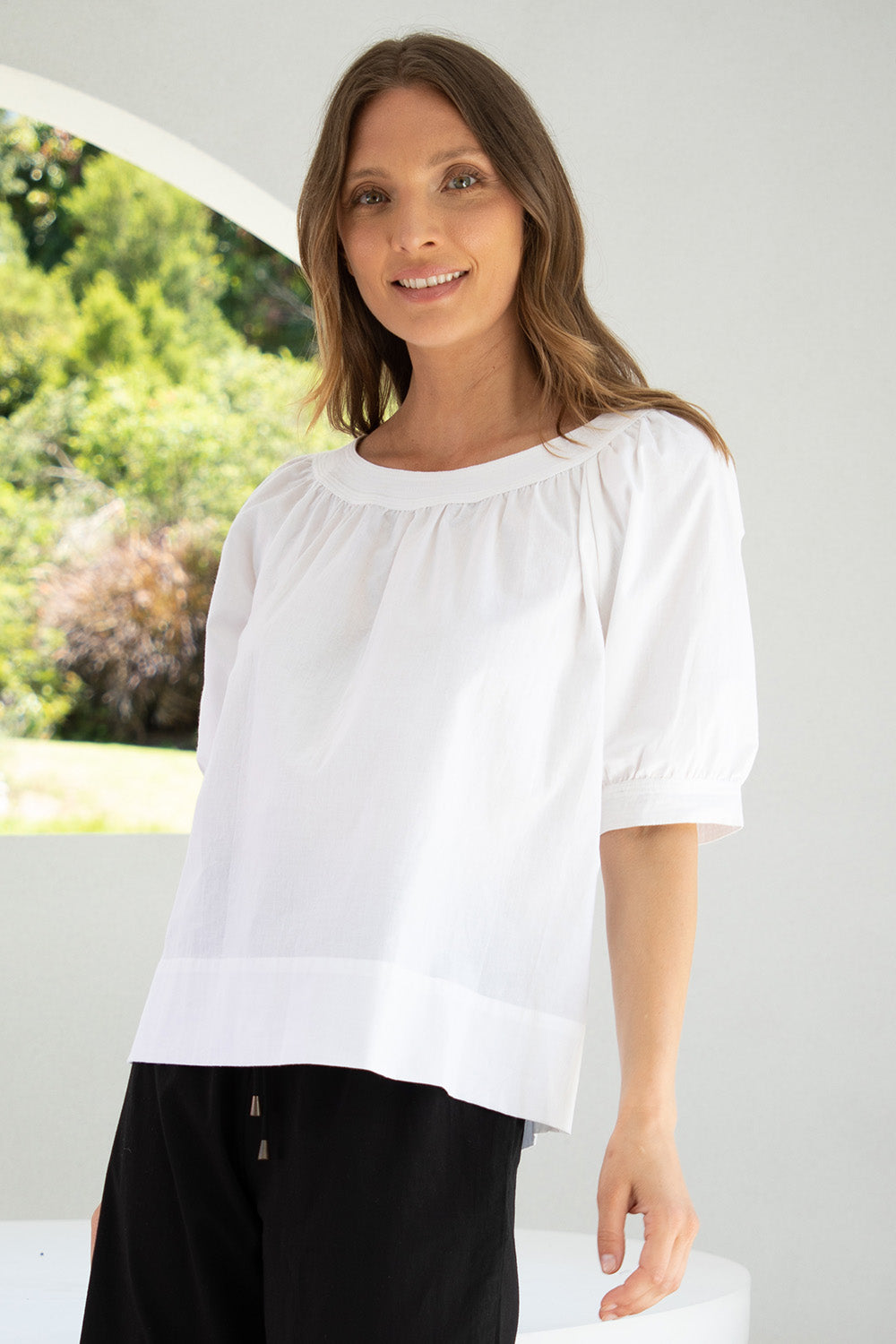 A model wearing the Bliss Top in colour White (White), from the front, cropped image