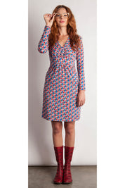 A model wearing the Lucia Dress in colour BlueFlags (Blue), from the front, showing the whole outfit