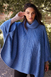 A model wearing the Claudine Poncho in colour Blue (Blue), from the front, showing the whole outfit