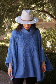 A model wearing the Claudine Poncho in colour Blue (Blue), from the front, showing the whole outfit