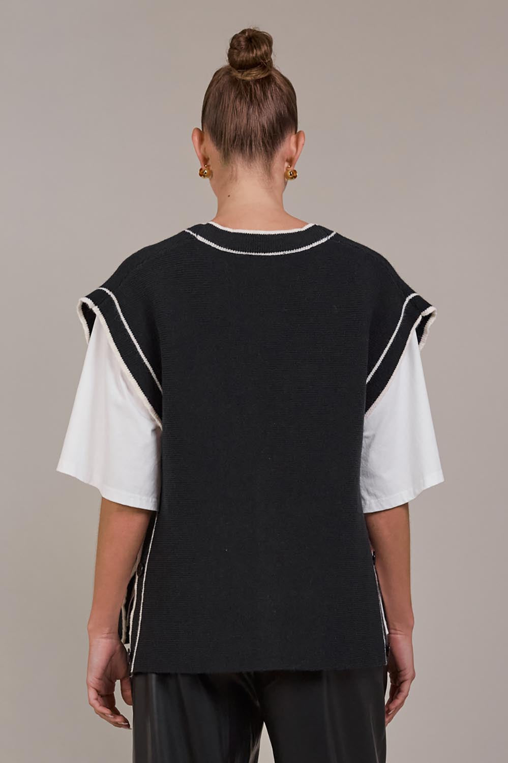 A model wearing the Avino Knit Vest in colour Black (Black), from the back