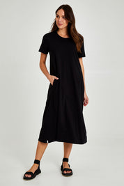 Model Madeline wearing size 10 of the Fundamental Adira Dress in colour Black (Black), from the front, showing the whole outfit