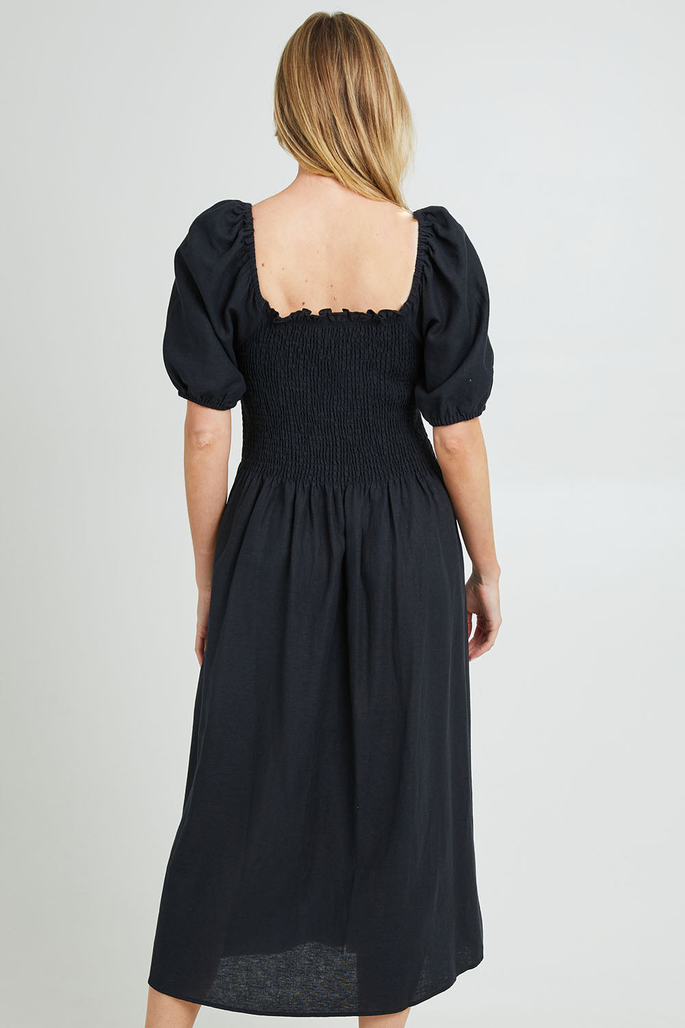 Model Grace wearing size 10 of the Ingrid Shoulder Dress in colour Coal (Black), from the back
