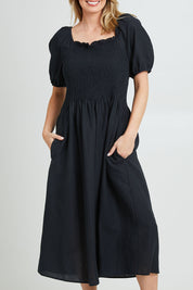 Model Grace wearing size 10 of the Ingrid Shoulder Dress in colour Coal (Black), from the front, cropped image