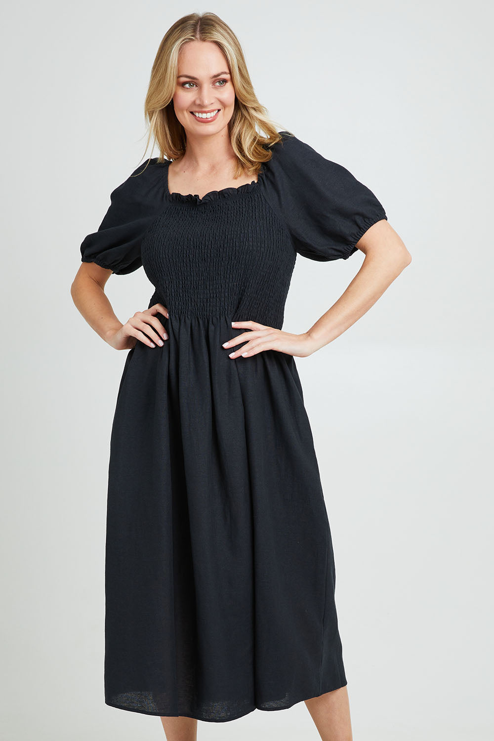Model Grace wearing size 10 of the Ingrid Shoulder Dress in colour Coal (Black), from the front, cropped image