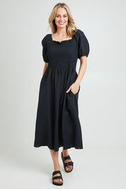 Model Grace wearing size 10 of the Ingrid Shoulder Dress in colour Coal (Black), from the front, showing the whole outfit
