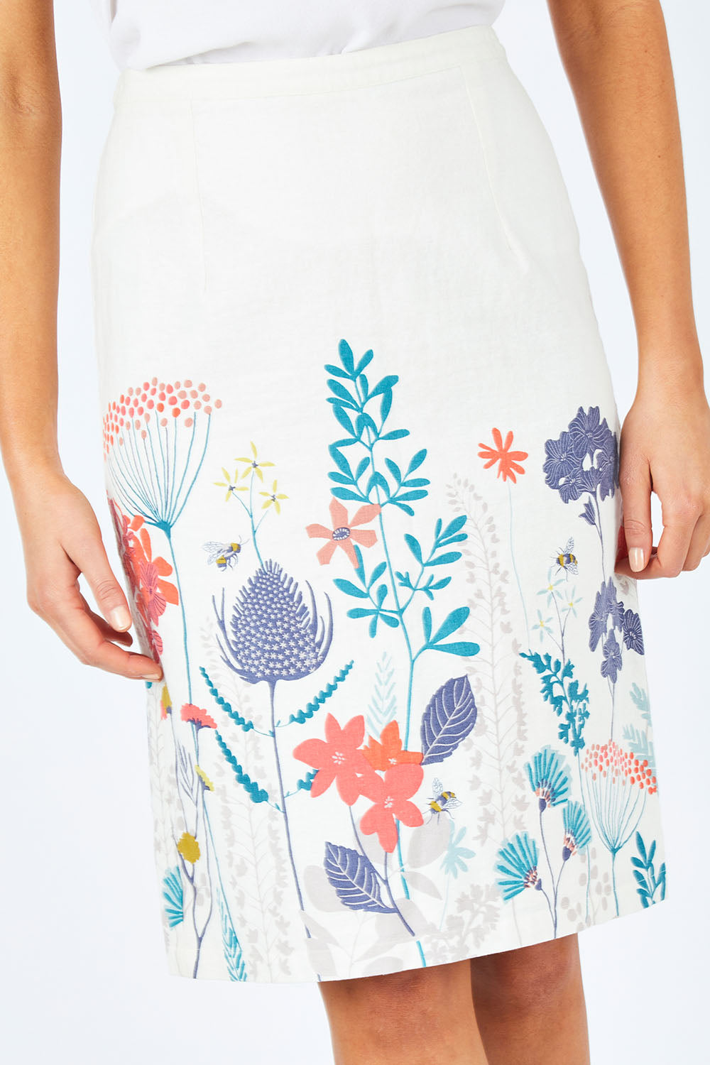 Model Madeline wearing size 10 of the Border Print Fitted Skirt in colour Floralmead (White), from the front, cropped image