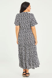 Model Terri-Leigh wearing size L of the Flutter Sleeve Maxi Dress in colour Blkprint (Black), from the back