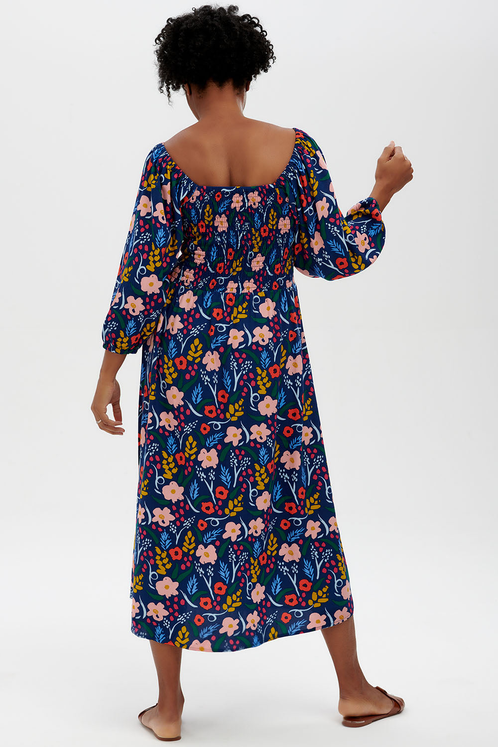 A model wearing the Raquel Shirred Dress in colour Blue (Blue), from the back
