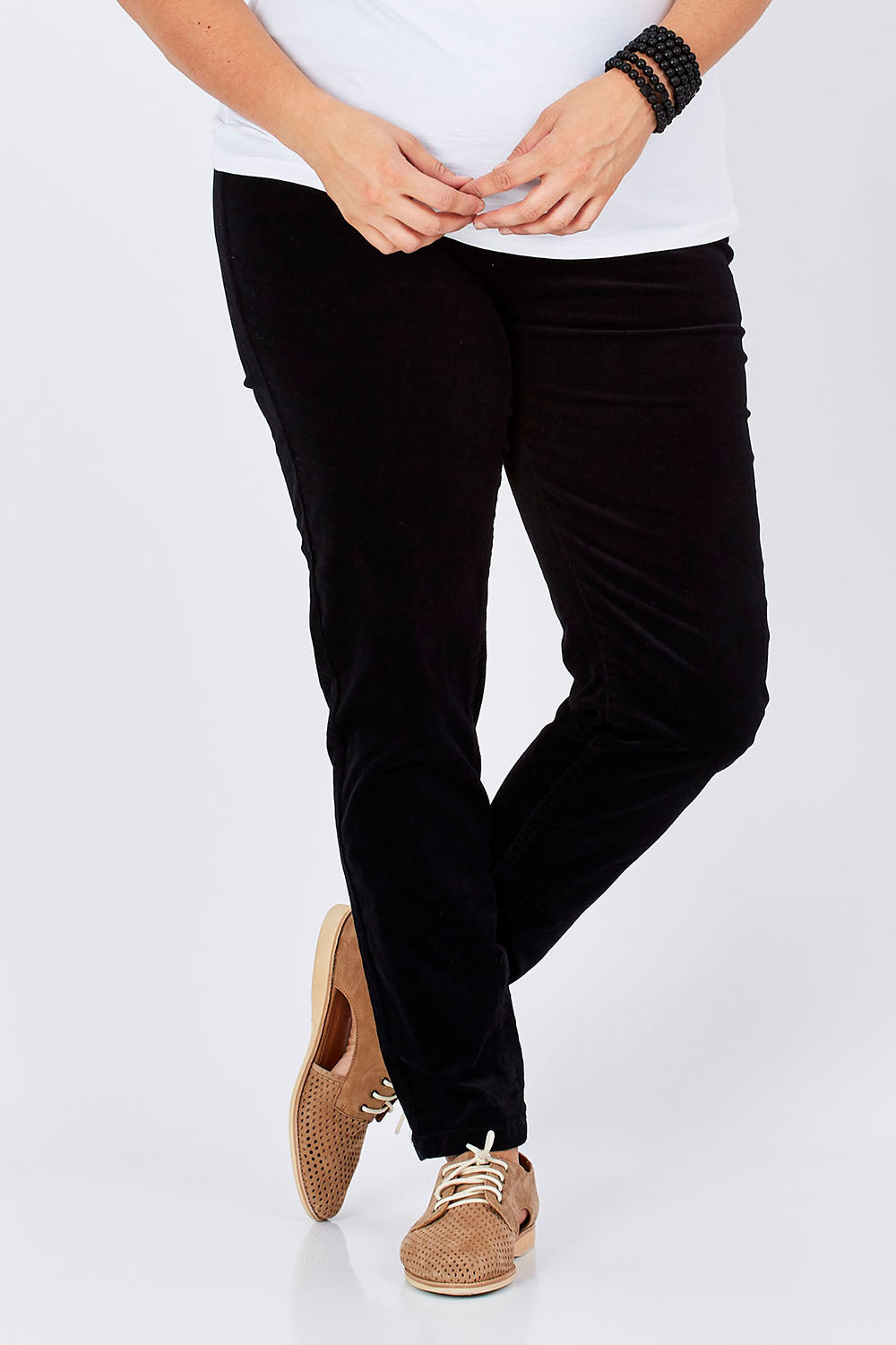 Model Mae wearing size 16 of the Skinny Leg Cord Pull On Pant in colour Black (Black), from the front, cropped image