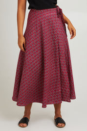Model Olivia wearing size OneSize of the Grace Cotton Wrap Skirt in colour Corfu (Red), from the front, cropped image