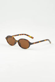 A model wearing The Bessette Sunglasses in colour Turtlebrwn, from the front, showing the whole outfit
