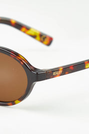 A model wearing The Bessette Sunglasses in colour Turtlebrwn, from the front, showing the whole outfit