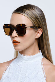 A model wearing the Danceteria Square Sunglasses in colour Turtle, from the front, showing the whole outfit