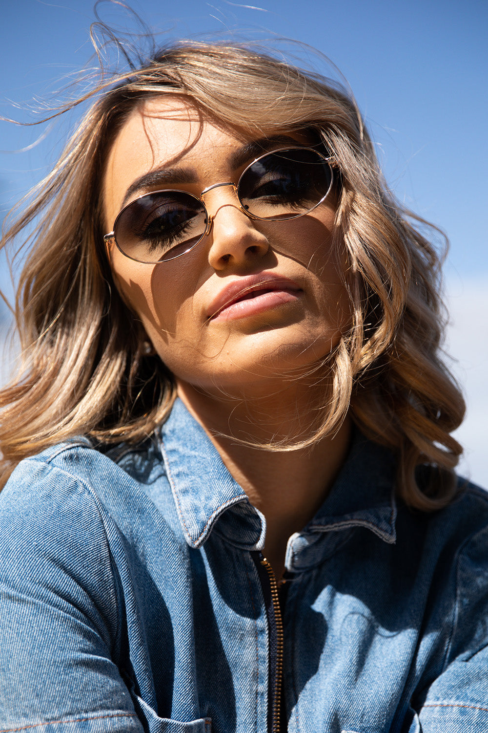 A model wearing the Helsinki Sunglasses in colour Goldgreen (Metallics), from the front, cropped image