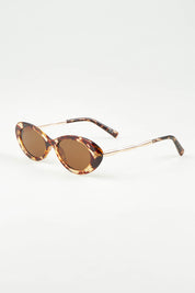 A model wearing the High Society Sunglasses in colour Honeyturtl, from the front, showing the whole outfit