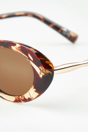 A model wearing the High Society Sunglasses in colour Honeyturtl, from the front, showing the whole outfit