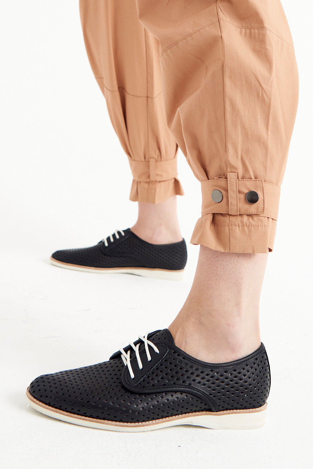 A model wearing the Derby Punch Flat in colour Black (Black), from the front, cropped image