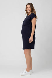 A model wearing the Roxie Nursing Dress in colour Navy (Blue), from the front, showing the whole outfit