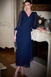 A model wearing the Sierra Wrap Dress in colour Navysparkl (Blue), from the front, showing the whole outfit
